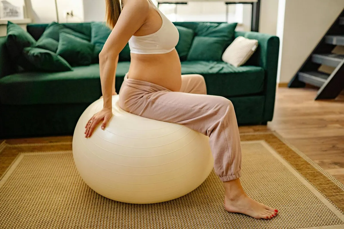 A pregnant woman training on a stability ball with a coach